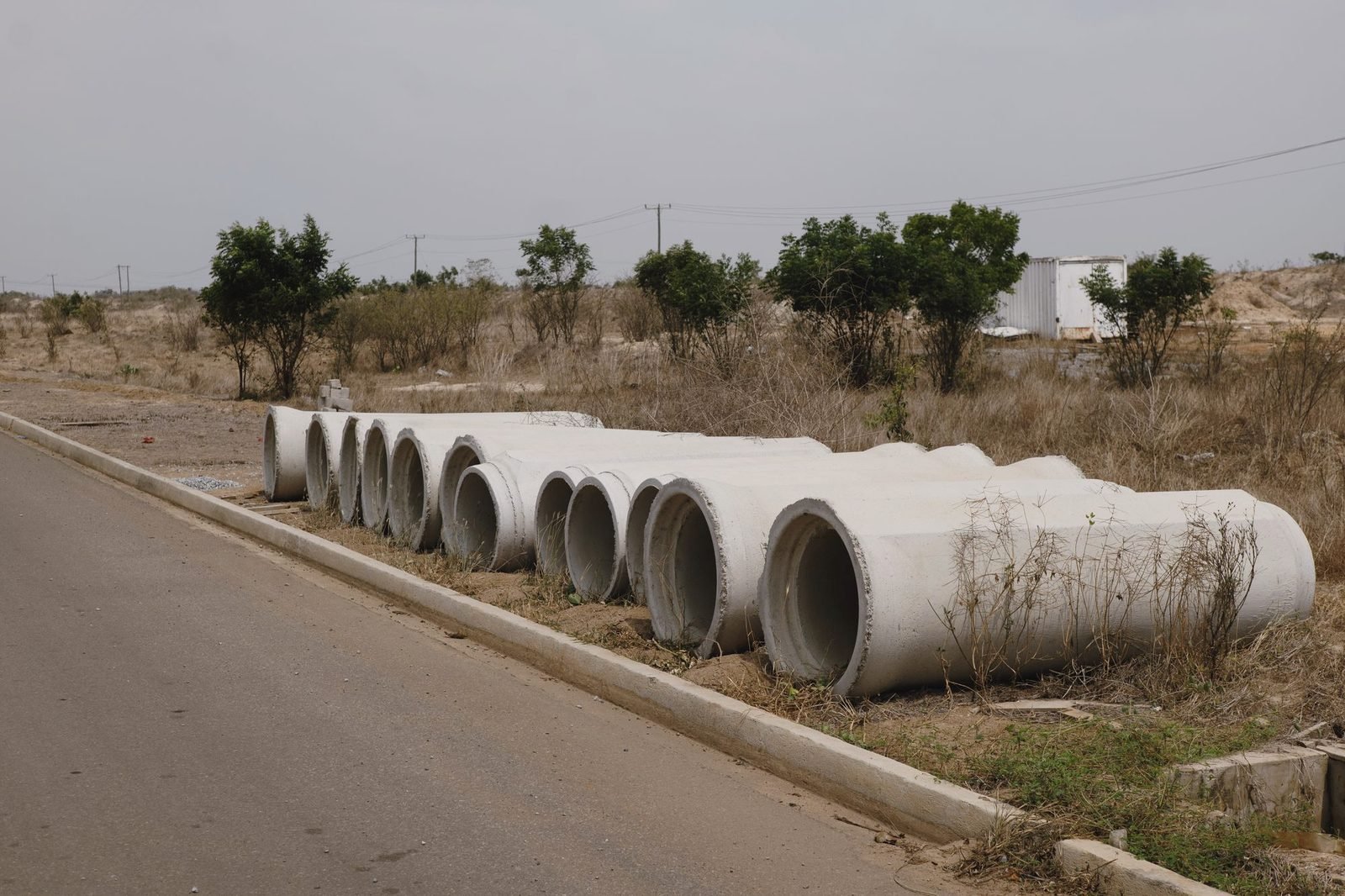 Concrete pipe sections lined up along a road edge