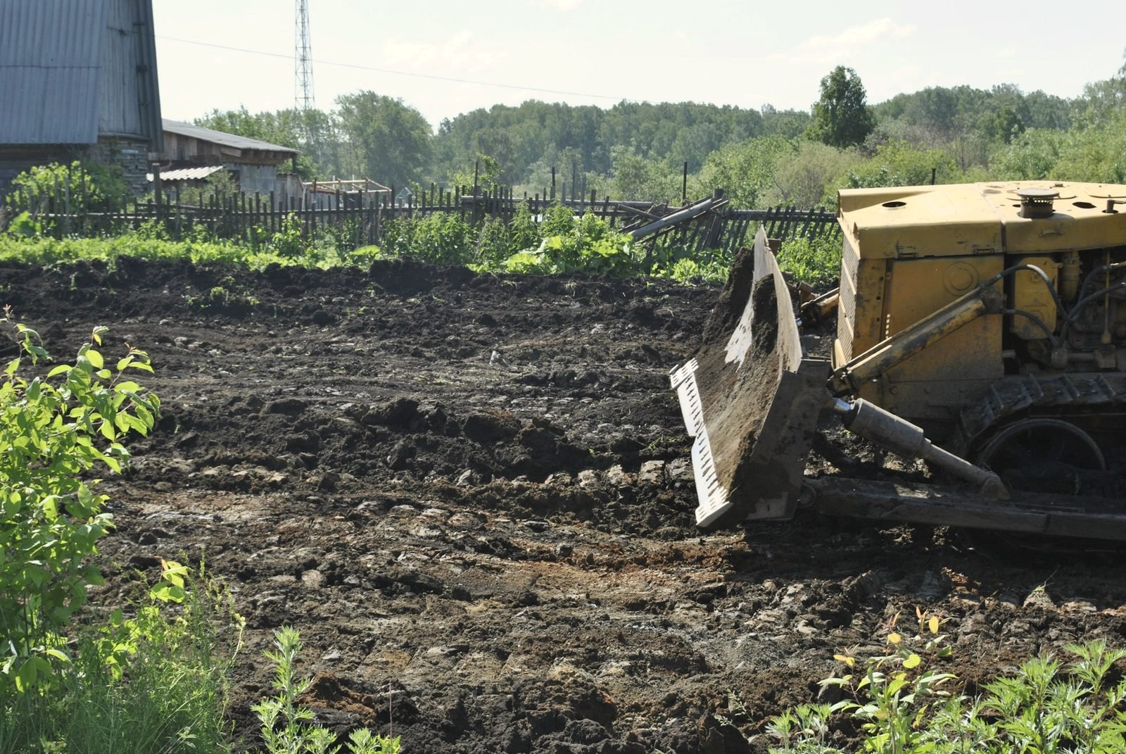 A dozer blade pushing dark soil across a cleared lot